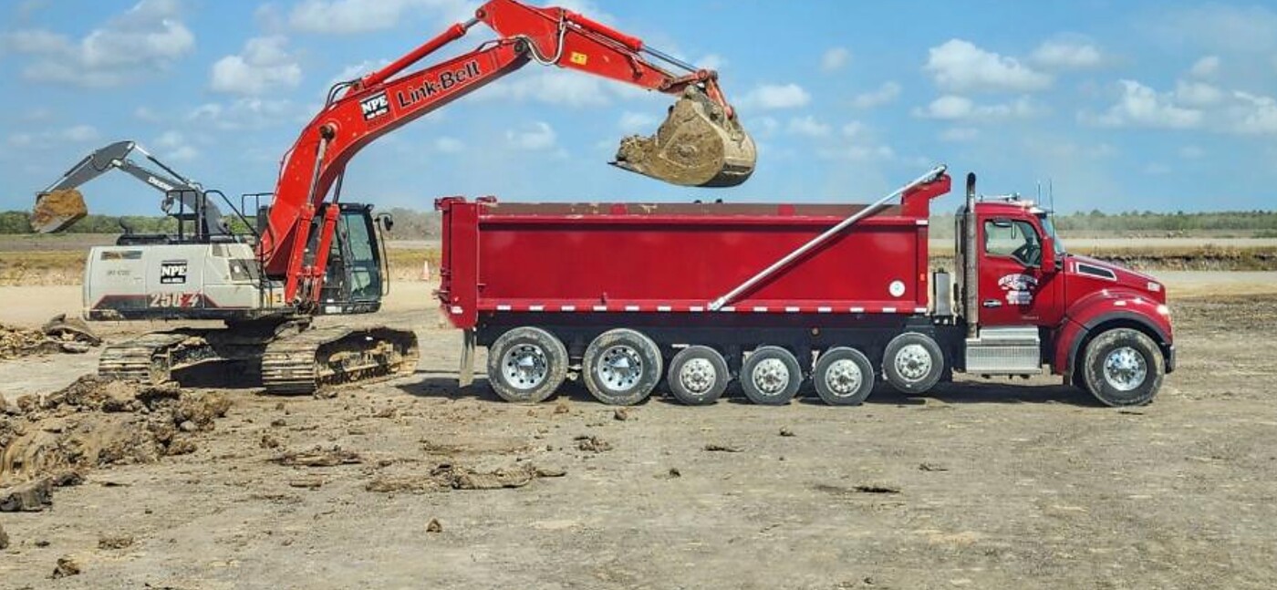 Excavator loading a One Way Enterprise dump truck on site