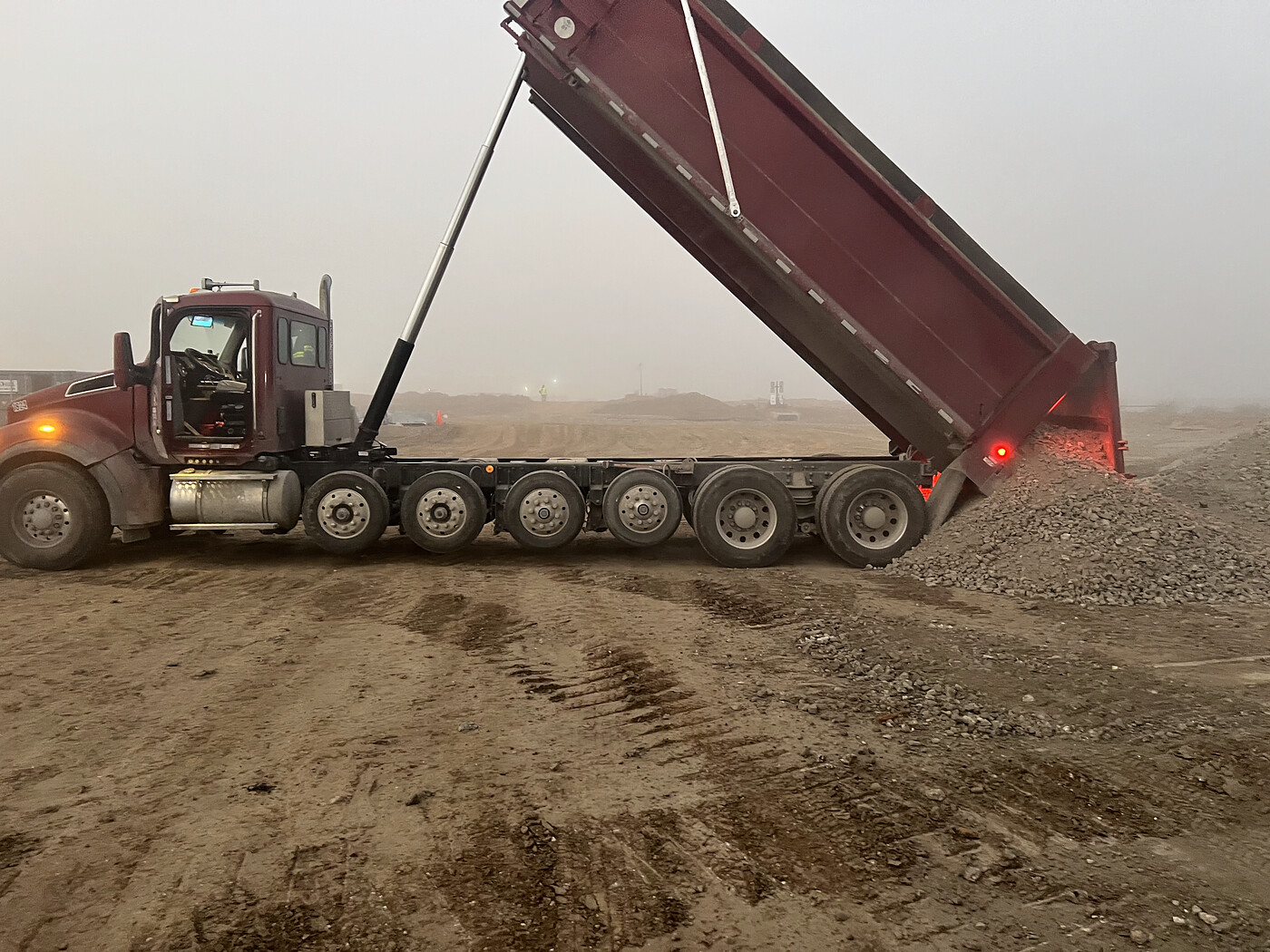 Dump truck dumping a load of fill dirt at a job site